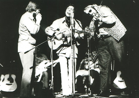 From left: Columbia Records staff producer Bob Johnston on harmonica, Leonard Cohen on vocals and guitar, and Charlie Daniels on fiddle, Isle of Wight Festival, Newport, England, August 31, 1970. Photo by Richard Imrie.