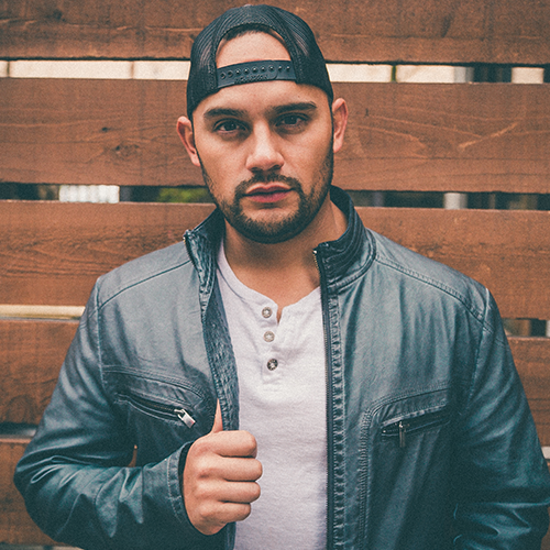 Songwriter Session: Frank Ray. Photo of Frank Ray where's a bomber jacket and a snapback hat on backwards.