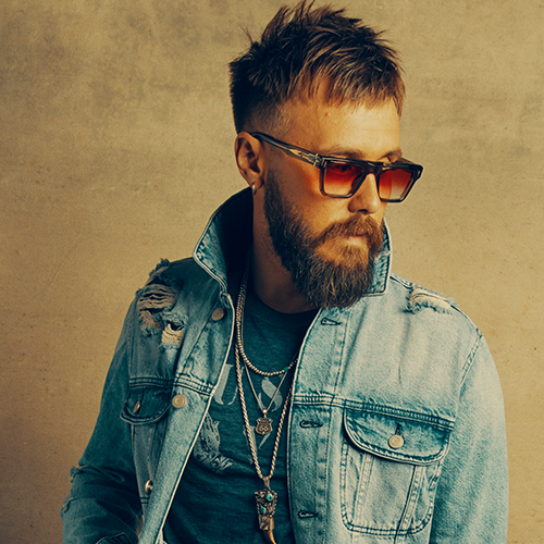 Photo of Elvie Shane wearing sunglasses and a denim jacket.