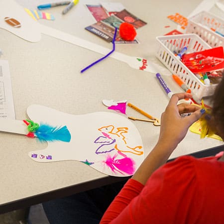 Photo of children working on crafts by decorating cutout-paper guitars