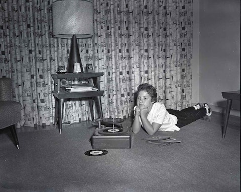 Brenda Lee laying on the floor with a record player and records