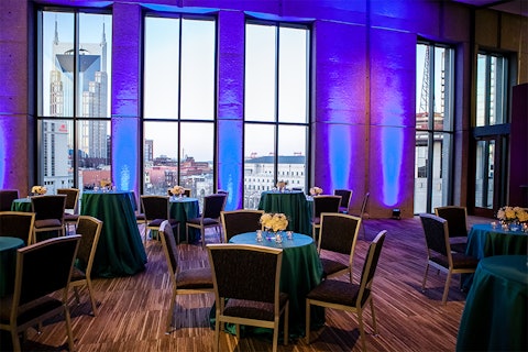 BMI Hall event space with decorative tables, blue accent lighting, and a downtown Nashville landscape view