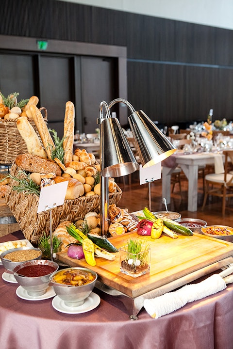 Catering spread on tables featuring appetizers, pastries, breads and a heating lamp