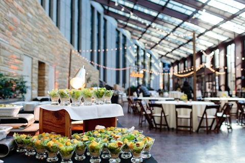 Event catering set up in the Conservatory of the Country Music Hall of Fame and Museum featuring gourmet appetizers and round tables with custom lighting