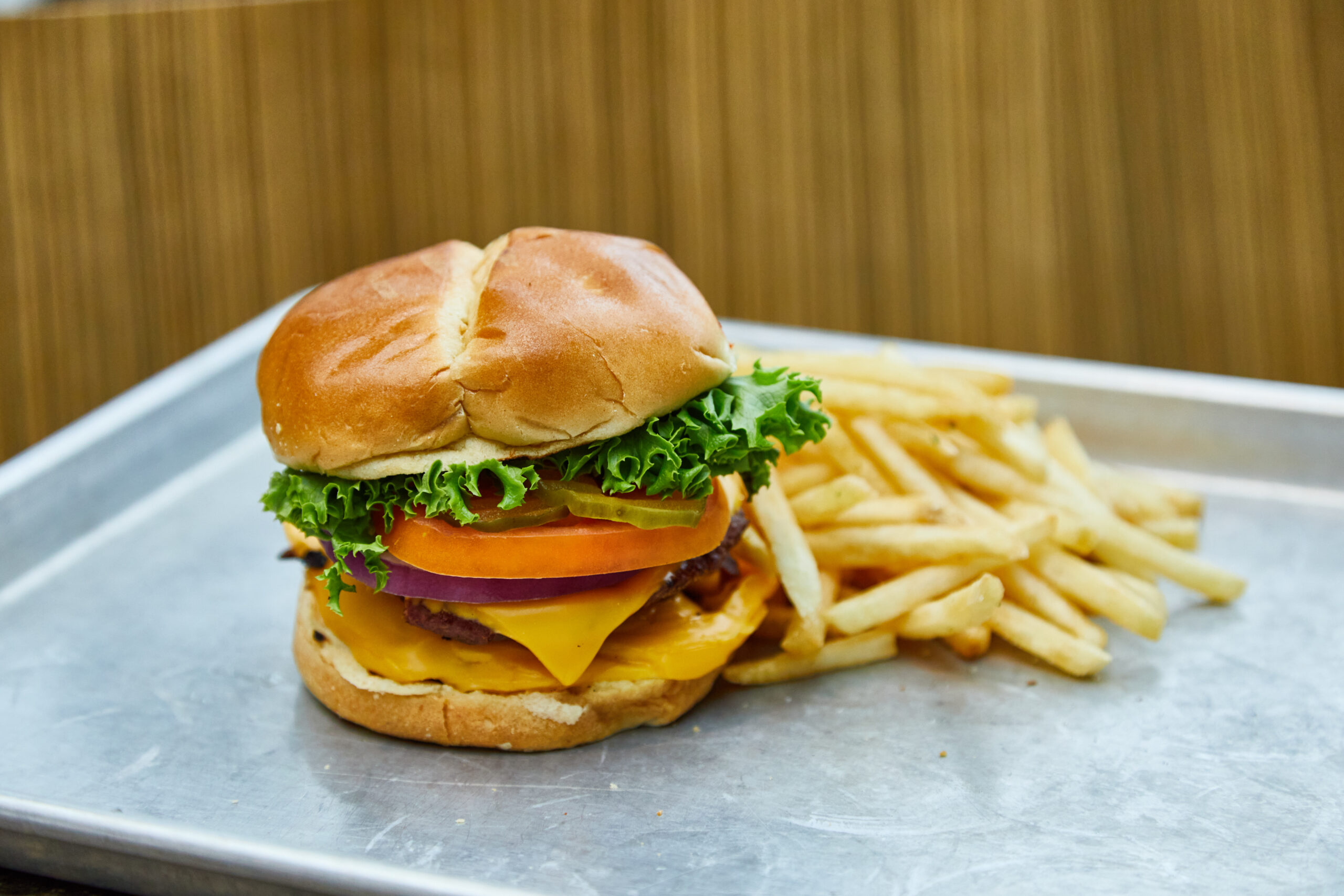 Cheeseburger with french fries on a metal tray