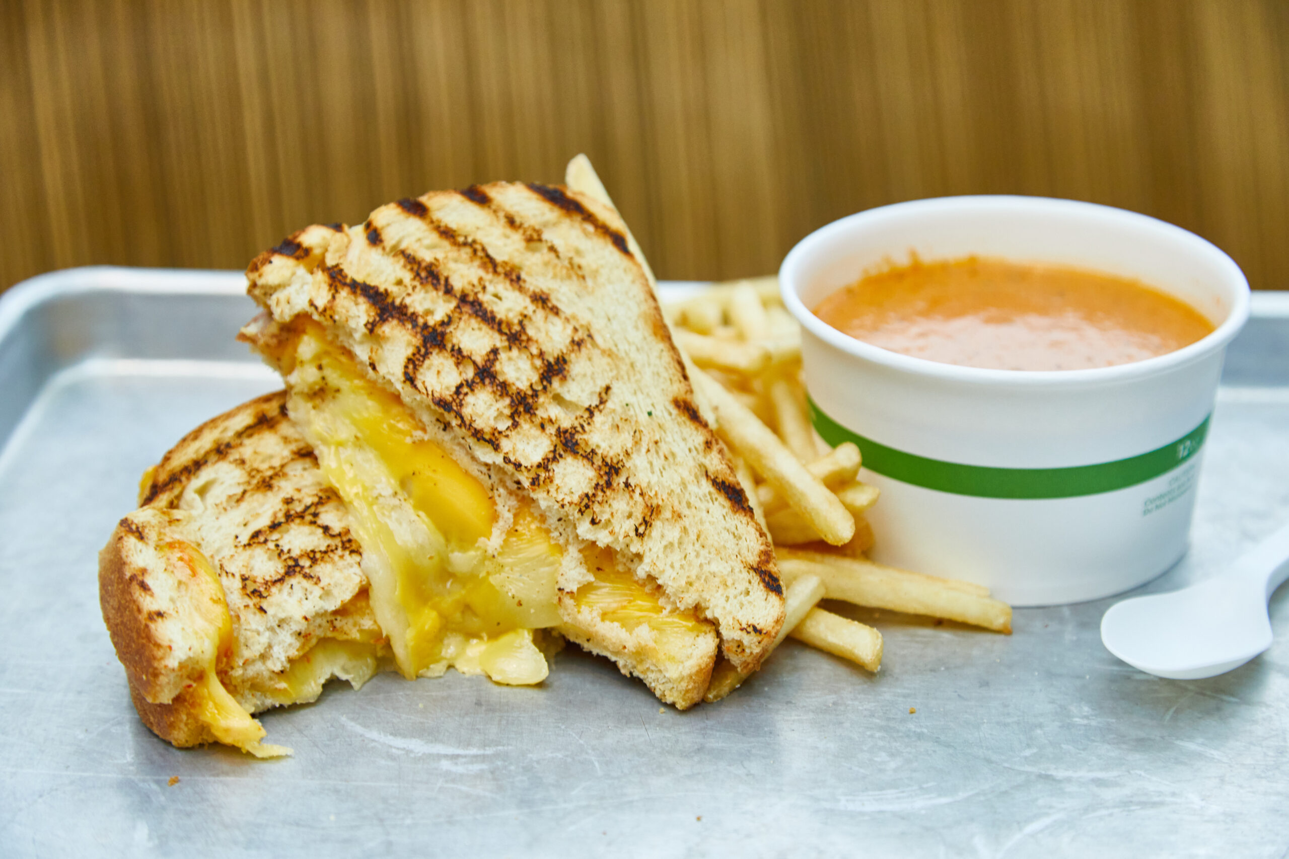 Grilled Cheese sandwich with french fries and a cup of tomato soup served on a metal tray