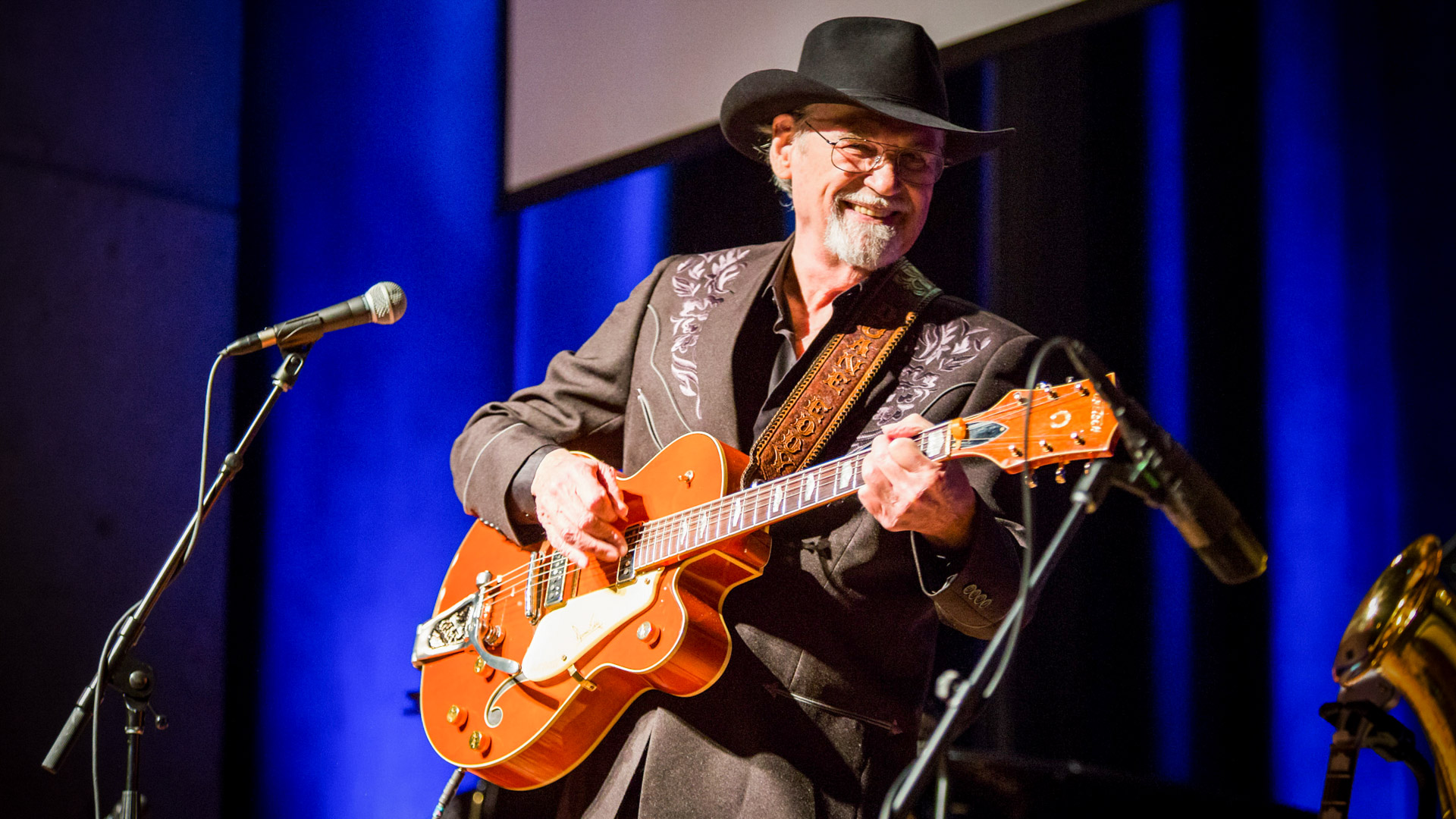 Older man performs on stage with an electric guitar
