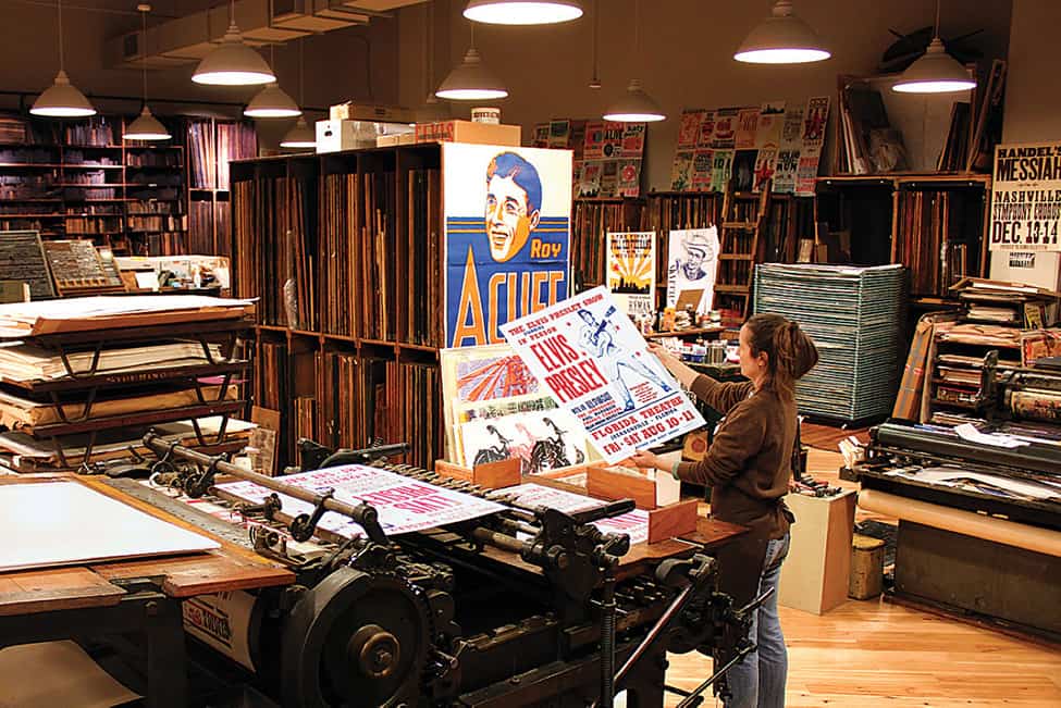 Printer at Hatch Show Print examines a print of an Elvis poster fresh off the press.