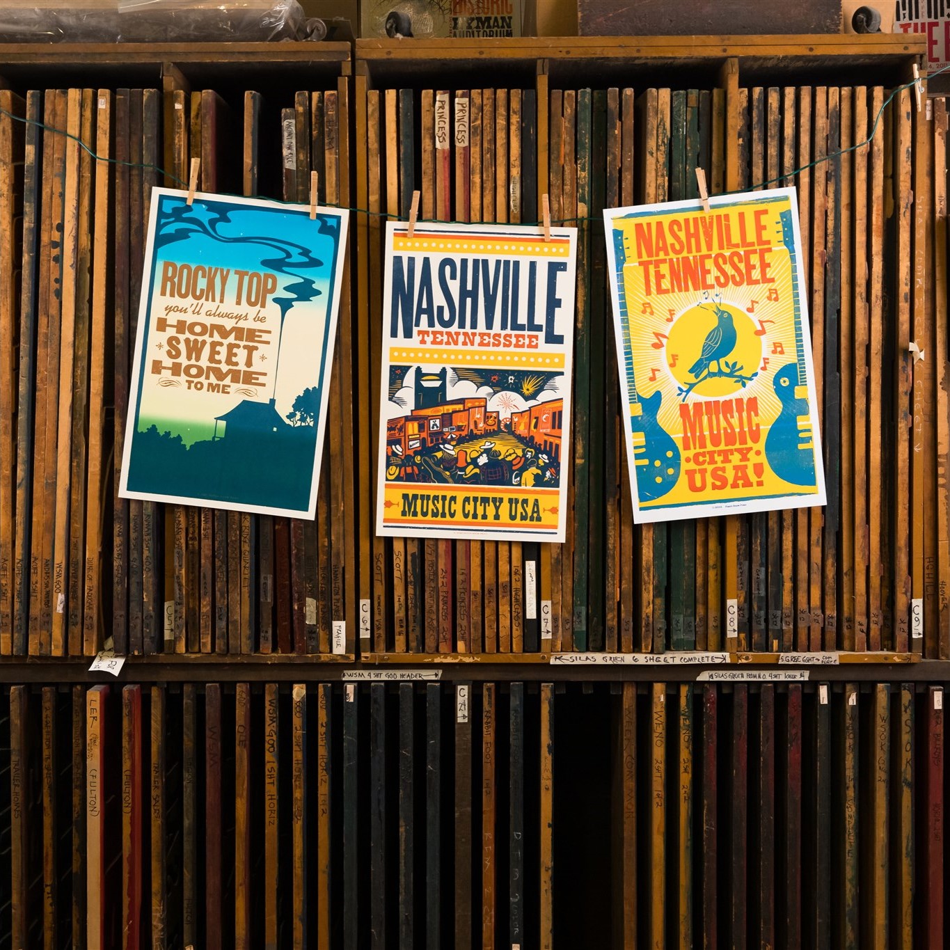 Posters highlighting Nashville hang on a wall of print blocks.